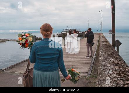 Langenargen Brautpaar Shooting an der Anlegestelle in Langenargen am Bodensee Langenargen am Bodensee : eine Frau mit Blumenstrauß beobachtet ein Brautpaar BEI einem Fotoshooting an der Anlegestelle. IM Hintergrund liegen Ausflugsschiffe und Segelboote auf dem Bodensee. Usage éditorial exclusif. *** Langenargen couple marié tirant sur la jetée de Langenargen sur le lac de Constance Langenargen sur le lac de Constance Une femme avec un bouquet de fleurs regarde un couple marié pendant une séance photo sur la jetée en arrière-plan sont des bateaux d'excursion et des voiliers sur le lac de Constance usage éditorial seulement Copyright : Banque D'Images
