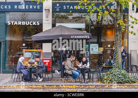 Les gens appréciant les boissons assis à l'extérieur au café Starbucks dans le centre de la ville Banque D'Images