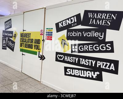 Manchester, Royaume-Uni - 26 septembre 2025 : un mur animé recouvert de logos et de signes audacieux créant un visuel urbain. Banque D'Images