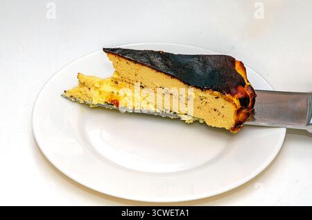 Morceau de désert de cheesecake brûlé basque sur une plaque en céramique Banque D'Images