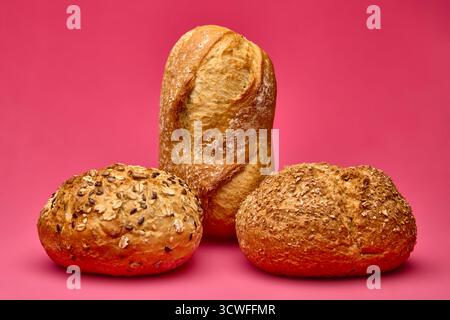 Pain vertical équilibré sur deux petits pains ronds sur fond rose. Composition conceptuelle des aliments symbolisant l'équilibre et la créativité dans la photogra de boulangerie Banque D'Images