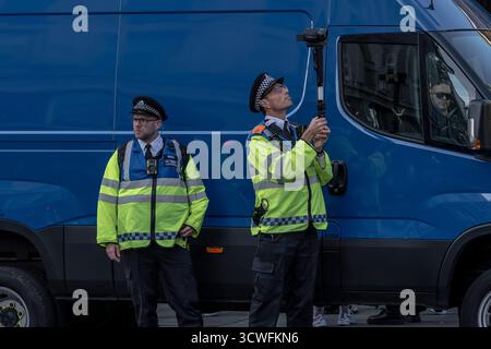 Londres, Royaume-Uni. 11 octobre 2025. (Photo) deux collecteurs de preuves de police se tiennent à côté d'un van de reconnaissance faciale met police, une unité mobile équipée de caméras et de logiciels pour effectuer une reconnaissance faciale en direct – qui implique la comparaison des visages capturés sur des images de caméra de surveillance avec une liste de surveillance de la police en temps réel. La police du met, la plus grande force de police de Grande-Bretagne, est actuellement en train de doubler son utilisation de la reconnaissance faciale en direct à 10 déploiements par semaine, contre quatre fois par semaine actuellement sur deux jours. Crédit : Guy Corbishley/Alamy Live News Banque D'Images
