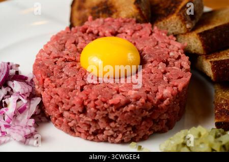 Tartare de bœuf Hovezi Tatarak style tchèque avec jaune d'œuf cru, pain grillé Topinki oignon rouge et Gherkin Banque D'Images