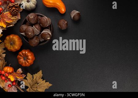 Muffins au chocolat disposés dans un bol avec des feuilles d'automne, de petites citrouilles et des baies sur un fond sombre plat confortable pour la récolte, l'action de grâce et Banque D'Images