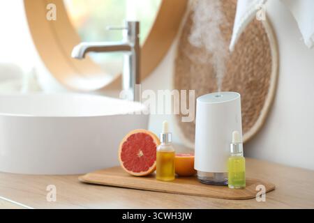 Humidificateur d'air moderne avec des huiles essentielles et pamplemousse sur la table dans la salle de bain, gros plan Banque D'Images
