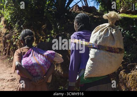 Lalibela, Ethiopie - Nov 2018: Deux femmes marchant et transportant des sacs sur leur dos Banque D'Images