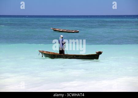 Stone Town (Zanzibar), Tanzanie - 6 janvier 2016 : un boutre (voilier traditionnel) en arrière-plan et un bateau de pêche bondé et un poissonnier dans le foreg Banque D'Images
