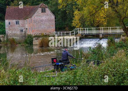 Sturminster Newton, Dorset, Royaume-Uni. 12 octobre 2025. Météo Royaume-Uni : couleurs d'automne à Sturminster Newton Mill, Dorset. Sturminster Newton Mill est l'un des rares moulins en activité sur la rivière Stour, qui fait partie d'une série d'anciens moulins à farine construits sur la rivière. C'est un moulin à eau entièrement fonctionnel produisant de la farine qui est vendue dans les magasins du Musée et du Moulin et est un merveilleux morceau d'archéologie industrielle. Pêcheur pêchant le long des berges. Crédit : Carolyn Jenkins/Alamy Live News Banque D'Images
