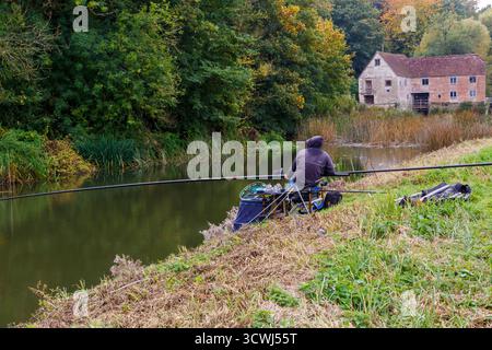 Sturminster Newton, Dorset, Royaume-Uni. 12 octobre 2025. Météo Royaume-Uni : couleurs d'automne à Sturminster Newton Mill, Dorset. Sturminster Newton Mill est l'un des rares moulins en activité sur la rivière Stour, qui fait partie d'une série d'anciens moulins à farine construits sur la rivière. C'est un moulin à eau entièrement fonctionnel produisant de la farine qui est vendue dans les magasins du Musée et du Moulin et est un merveilleux morceau d'archéologie industrielle. Pêcheur pêchant le long des berges. Crédit : Carolyn Jenkins/Alamy Live News Banque D'Images
