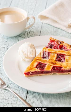 La tarte chaude et la crème glacée fraîche se marient parfaitement avec le café à la vapeur dans une lumière douce Banque D'Images