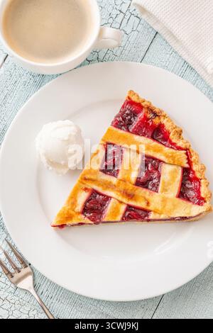 La tarte chaude et la crème glacée fraîche se marient parfaitement avec le café à la vapeur dans une lumière douce Banque D'Images