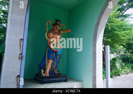 Statue de gardien colorée dans une alcôve de porte se dresse avec un poing levé et une épée au complexe Bouddha Sharira Stupa, encadré par l'arche et ses environs Banque D'Images