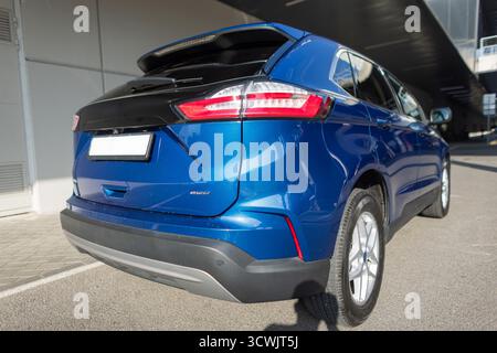 SUV bleu moderne garé sur la rue de la ville près du bâtiment en béton, vue arrière avec feux arrière. Voiture multisegment moderne compacte en couleur bleue, vue arrière avec D. Banque D'Images