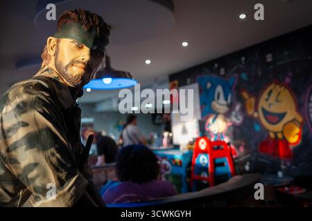 Une figurine Metal Gear Solid est exposée dans une arcade rétro mettant en vedette des œuvres murales Sonic le hérisson et PAC-Man Banque D'Images