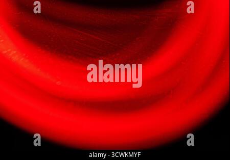 Flou de mouvement de lumière rouge abstrait avec des lignes courbes sur fond sombre, texture d'onde lumineuse avec effet d'énergie vibrant Banque D'Images