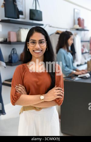 Heureuse jeune femme adjointe indienne qui pose sur la surface de vente Banque D'Images