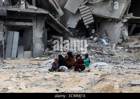 Gaza. 12 octobre 2025. Les Palestiniens sont assis parmi les décombres des bâtiments détruits après leur retour à Khan Younis, dans le sud de la bande de Gaza, le 12 octobre 2025. L’accord de cessez-le-feu entre Israël et le Hamas est entré en vigueur vendredi. Crédit : Rizek Abdeljawad/Xinhua/Alamy Live News Banque D'Images