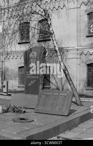 Un mémorial de la seconde Guerre mondiale dédié aux travailleurs tombés au combat de l'usine d'accessoires et d'isolants (AIZ) se dresse sur le terrain de l'usine à Sloviansk, en RSS d'Ukraine, sur cette photo des années 1980. Le monument présente une stèle de granit avec un soldat gravé et la célèbre ligne « et le monde sauvé se souvient », une base de flamme éternelle, et une plaque énumérant les noms des morts. Cette image en noir et blanc est un exemple poignant de la culture du souvenir au sein des entreprises industrielles soviétiques Banque D'Images
