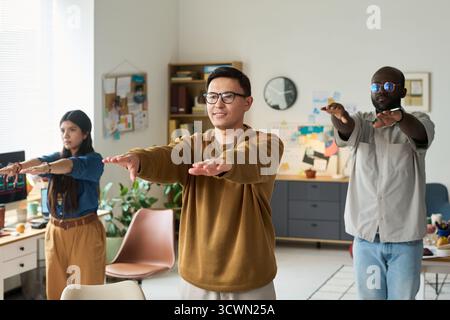 Adultes multiethniques pratiquant l'exercice d'étirement en groupe à l'intérieur Banque D'Images