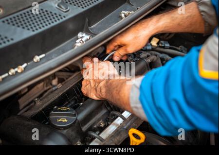 Mains mécaniciens effectuant l'entretien et la réparation sur un moteur automobile moderne Banque D'Images