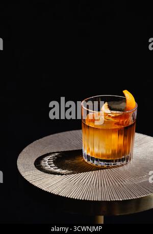 Cocktail à l'ancienne sur une table en or avec fond noir. Banque D'Images