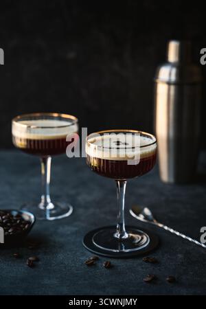 Gros plan des cocktails espresso martini et shaker sur fond sombre. Banque D'Images
