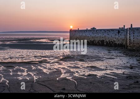La lumière chaude paisible du coucher de soleil se reflète sur la plage de sable à marée basse Banque D'Images