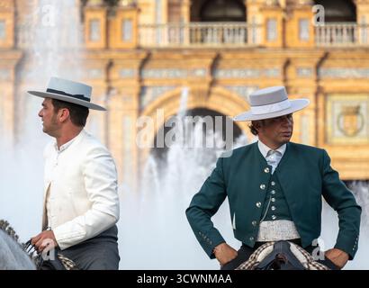 Sevilla, Espagne - 23 avril 23 : deux hommes à cheval portant une tenue espagnole traditionnelle, avec une fontaine en arrière-plan Banque D'Images