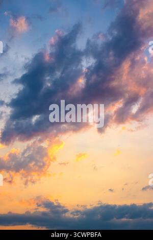 paysage nuageux sombre au coucher du soleil. nuages orange-violet sur un gradient jaune-bleu de ciel dans la lumière du soir. changement climatique dramatique. bruit de fond de prévision du vent. Banque D'Images