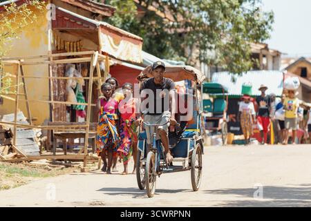 Miandrivazo, Madagascar - 11 octobre 2025 : trajet quotidien à Miandrivazo, montrant les rickshaws à cycle brillamment couverts utilisés pour le transport de passagers. Banque D'Images