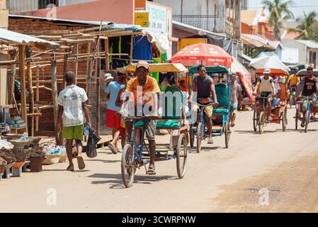 Miandrivazo, Madagascar - 11 octobre 2025 : trajet quotidien à Miandrivazo, montrant les rickshaws à cycle brillamment couverts utilisés pour le transport de passagers. Banque D'Images