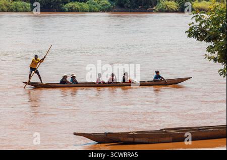 Miandrivazo, Madagascar - 11 octobre 2025 : les Malgaches locaux voyagent en pirogue traditionnelle sur la rivière rouge-brun près de Miandrivazo, Menabe. Banque D'Images