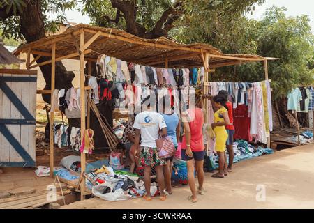 Miandrivazo, Madagascar - 11 octobre 2025 : des femmes et des jeunes gens de la région qui achètent des vêtements d'occasion à un étal de rue dans la zone du marché de Mian Banque D'Images