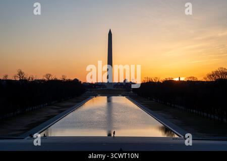 Vue du Washington Monument reflété dans la piscine réfléchissante sous un ciel vibrant lever de soleil, projetant de longues ombres à travers le paysage, Washington, D. Banque D'Images