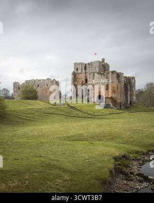 Vue des murs de pierre altérés d'un château médiéval s'élèvent d'un champ vert vibrant sous un ciel sombre, un témoignage de l'histoire, Penrith, Angleterre, United Banque D'Images