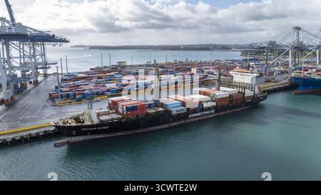 Auckland, Nouvelle-Zélande - 19 septembre 2025 : vue aérienne d'un cargo, Moana Chief, domine la scène, amarré au milieu d'une mer de conteneurs colorés sous un ciel nuageux à Tooley Street. Banque D'Images