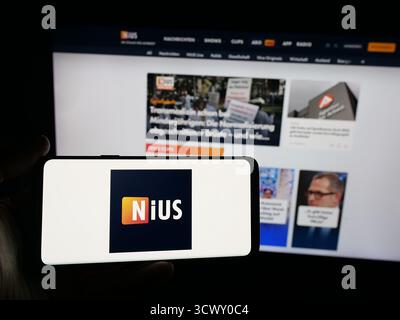 Stuttgart, Allemagne - 10-06-2025 : personne tenant un smartphone avec le logo de la société allemande Nius sur l'écran devant le site Web. Banque D'Images