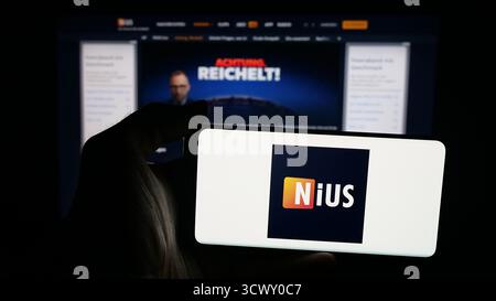 Stuttgart, Allemagne - 10-06-2025 : personne tenant un téléphone portable avec le logo de la société allemande Nius sur l'écran en face de la page Web. Banque D'Images