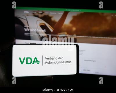 Stuttgart, Allemagne - 10-06-2025 : personne tenant un smartphone avec le logo de German Verband der Automobilindustrie (VDA) sur l'écran devant le site Web. Banque D'Images