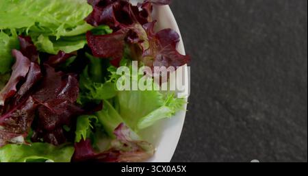 Affichant un bol en céramique blanche contenant de la laitue verte et rouge sur le comptoir de cuisine, espace de copie Banque D'Images