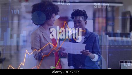 Examinant le rapport imprimé des collègues portant un blazer et une chemise en Jean dans le salon du bureau, avec un ordinateur portable Banque D'Images