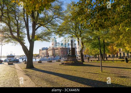 Vue panoramique automnale d’un monument-fontaine historique sur une place ensoleillée à Stockholm, Suède, encadrée d’arbres verts et jaunes Banque D'Images