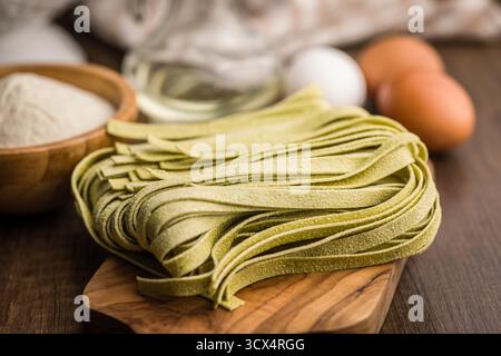 Pâtes tagliatelles vertes sur planche à découper sur une table en bois. Banque D'Images