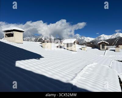 Les toits enneigés avec des cheminées distinctes créent un paysage hivernal serein sous un ciel bleu vif, beauté de la nature et de l'architecture, saison Banque D'Images
