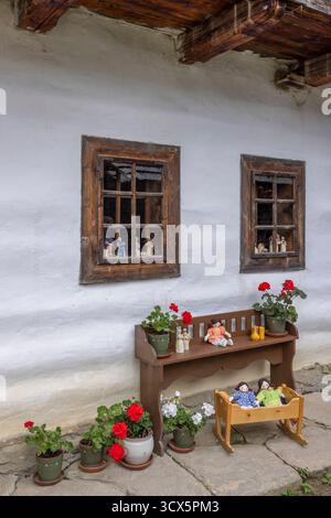 Mur de maison folklorique slovaque traditionnel décoré de fleurs en pot, de poupées faites à la main et de meubles en bois Banque D'Images