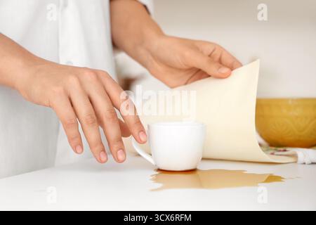 Femme essuyant le café renversé sur le comptoir dans la cuisine, gros plan Banque D'Images