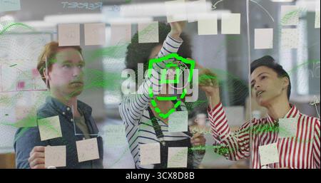 Collaboration de trois collègues mettant en évidence des notes sur panneau de verre dans le bureau, avec superposition numérique Banque D'Images