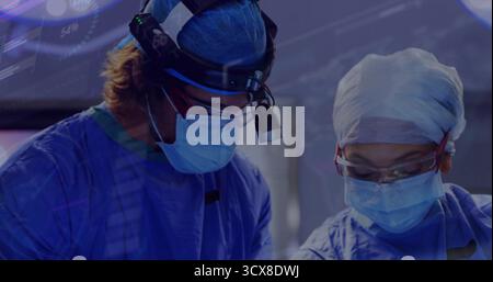 Chirurgiens opératoires en bleus pratiquant la chirurgie en salle d'opération, avec des instruments phares Banque D'Images