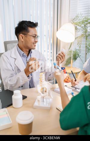 Groupe de médecins et infirmières consultant à propos d'un cas complexe de patients en cabinet hospitalier. Équipe analysant les données médicales et discutant des plans de diagnostic pour Banque D'Images