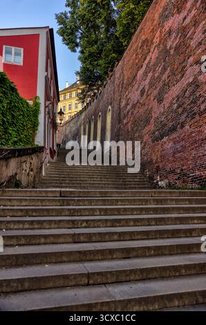 Un étroit escalier en pierre descend à travers le quartier historique de Malá Strana à Prague, offrant une vue panoramique sur les toits en direction du centre-ville Banque D'Images